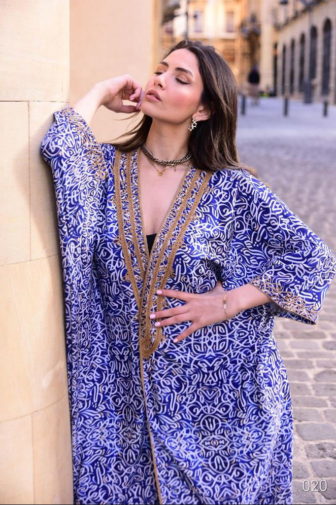 A woman wearing a blue abaya adorned with delicate Arabic lettering accents, adding a touch of cultural elegance to her attire.