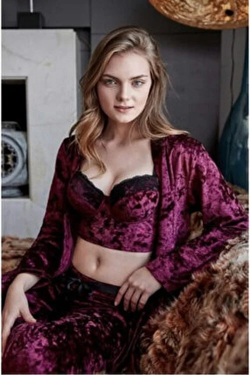 Woman wearing Popjammies velvet pyjama set with lace bralette and robe, sitting on a plush fur blanket.