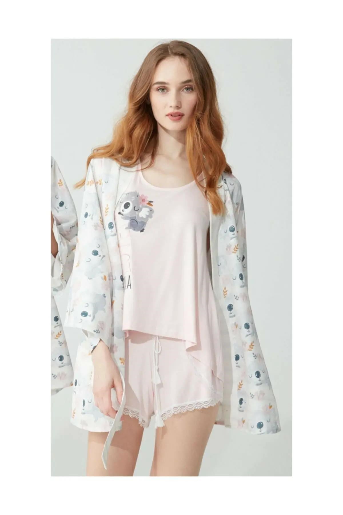 A woman wearing a pink Koala-themed pyjama set from Popjammies. The set includes a sleeveless top with a cute koala print and matching shorts with lace trim, paired with a light kimono-style robe featuring the same koala print. Perfect for a comfortable and adorable look at home.