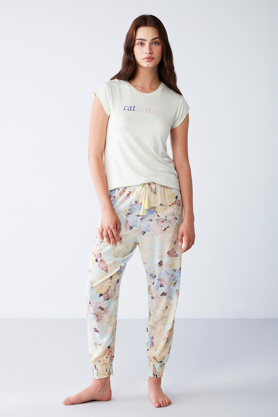 Woman wearing Popjammies' Catherine's Floral Pyjama Set, featuring a short-sleeve top and pastel floral drawstring pants.