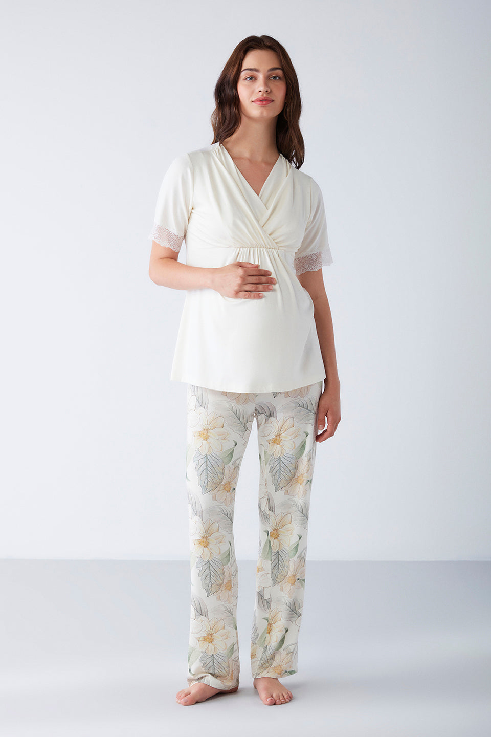 Woman wearing Popjammies Floral Maternity Pajama Set with a wrap-style top and floral pants, standing in a light background.