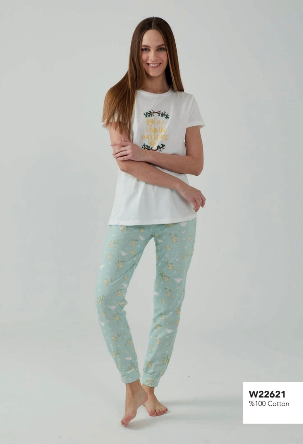 Model wearing a Popjammies mint floral pyjama set, featuring a white top with a motivational graphic and mint-colored floral print pants, standing barefoot.