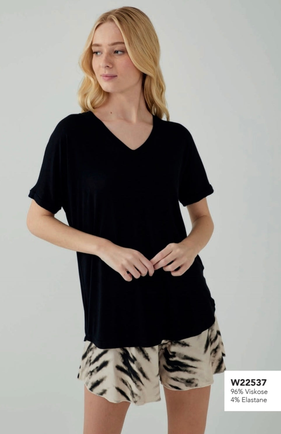 Model wearing Popjammies Black Elegance Pyjama Set with a black V-neck top and black and beige tie-dye shorts.