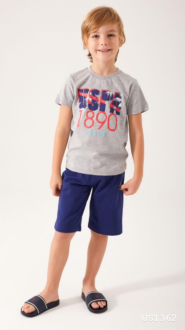 Boy wearing a grey top with "USPA 1890" and blue shorts from Popjammies, standing and smiling.