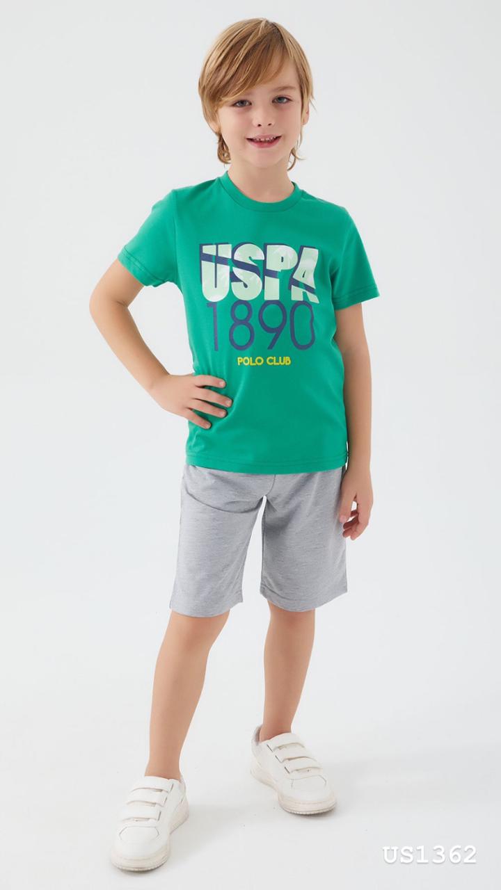 Smiling boy wearing a green top with "USPA 1890 Polo Club" graphic, paired with grey shorts pyjama set from Popjammies.