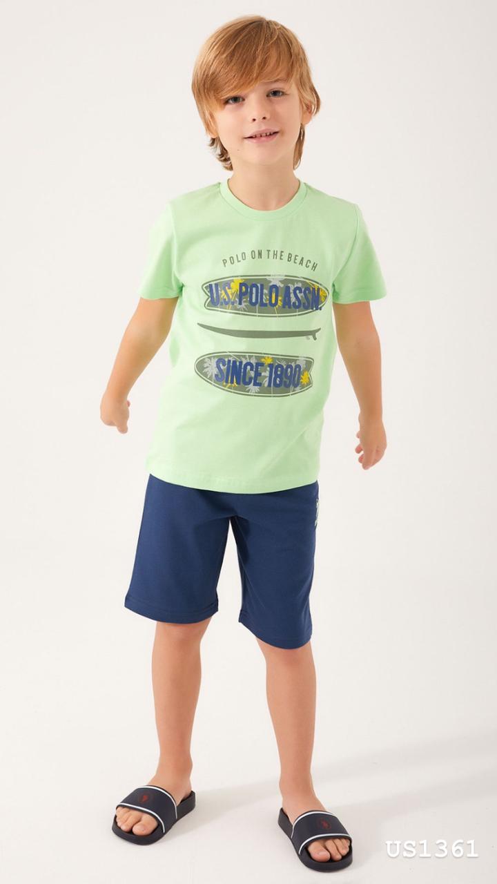 Boy wearing a light green top with surfboard graphics and navy blue shorts from Popjammies, standing and smiling.