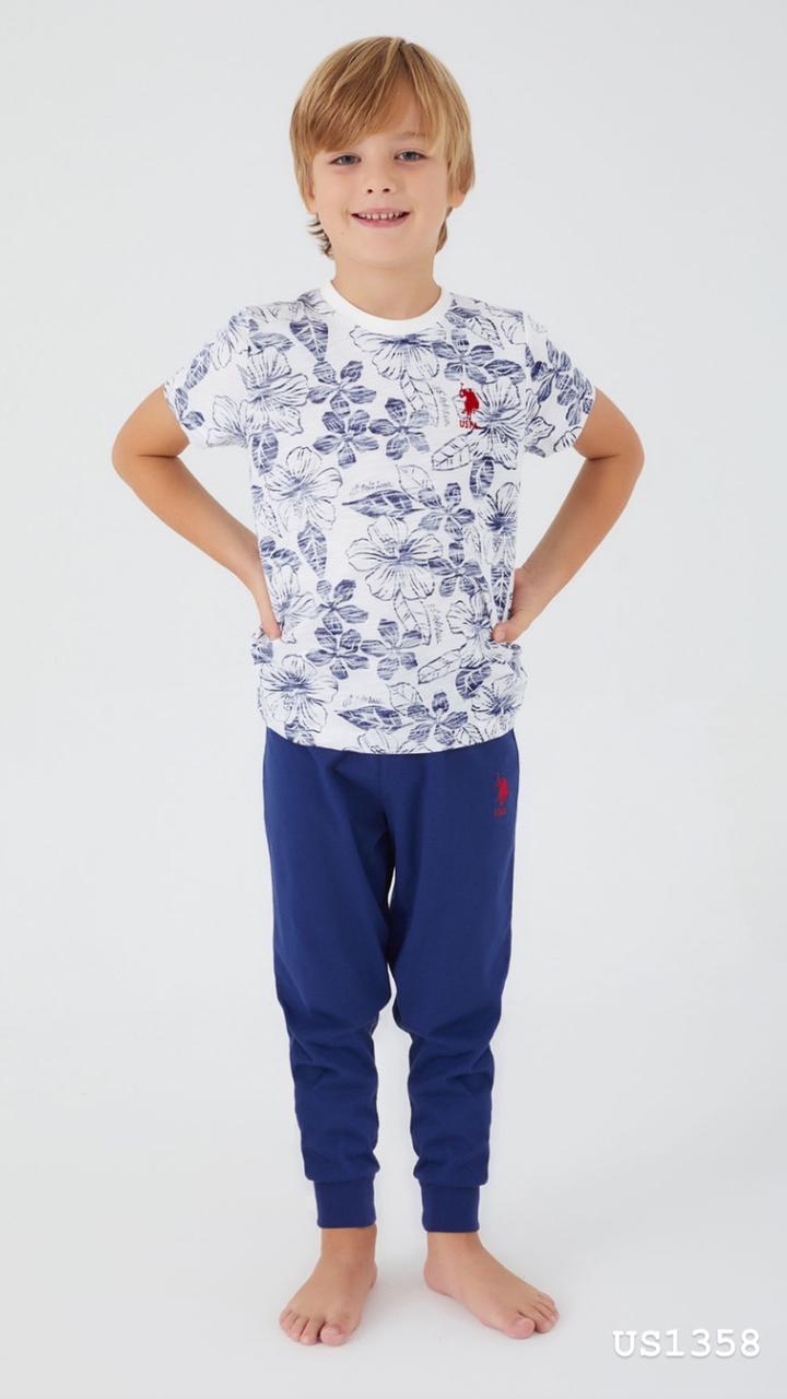 Boy posing in Popjammies floral print pyjama set, featuring white top with floral print and navy blue pants.