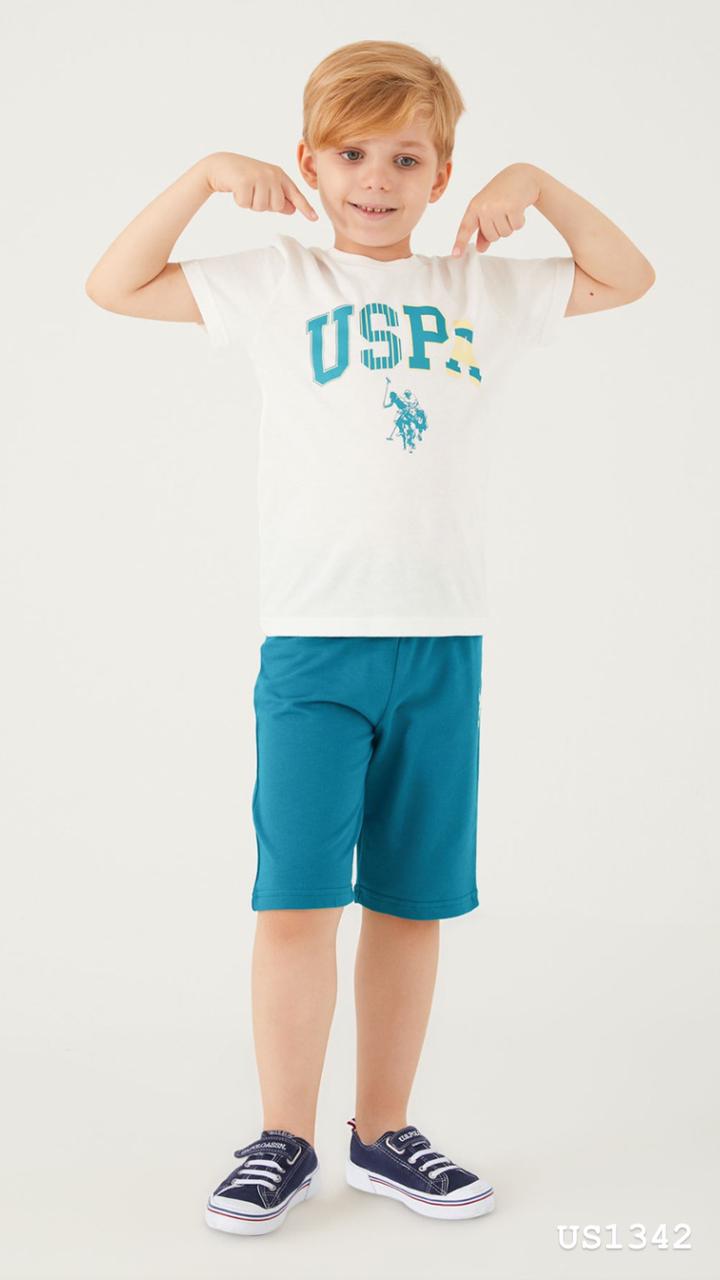 Boy pointing at his white t-shirt with a teal USPA logo and teal shorts from Popjammies pyjama set.