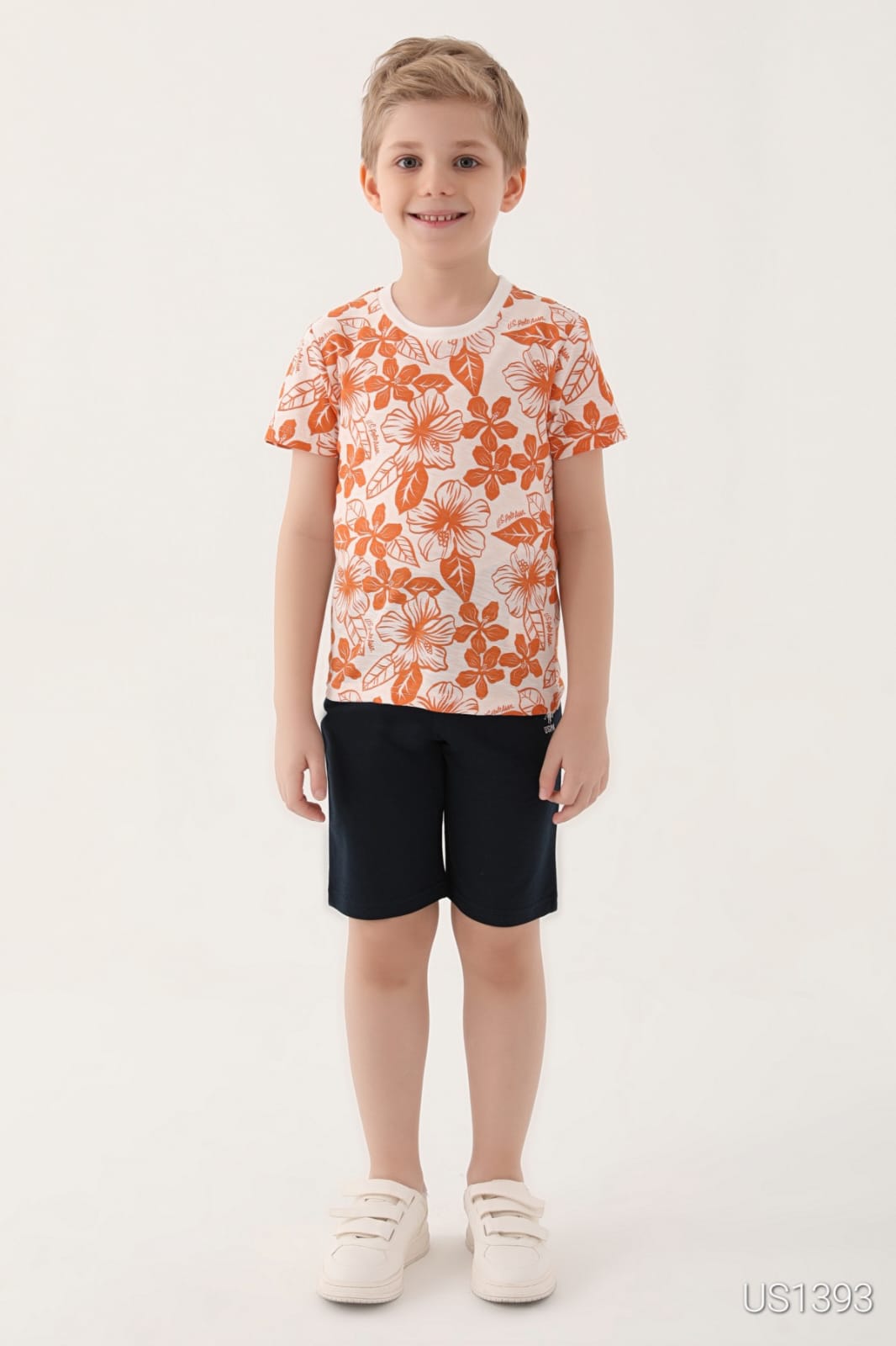 Smiling boy wearing a vibrant pyjama set with an orange floral print top and navy blue shorts from Popjammies.