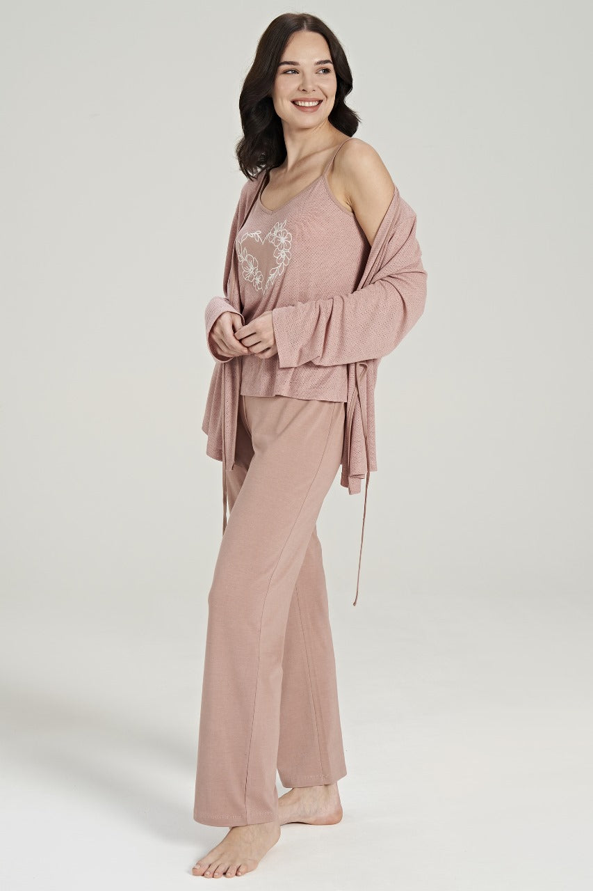 Smiling woman wearing a three-piece pink loungewear set from Popjammies, featuring a spaghetti strap top with a floral heart design, matching relaxed-fit pants, and a cozy long-sleeve cardigan.