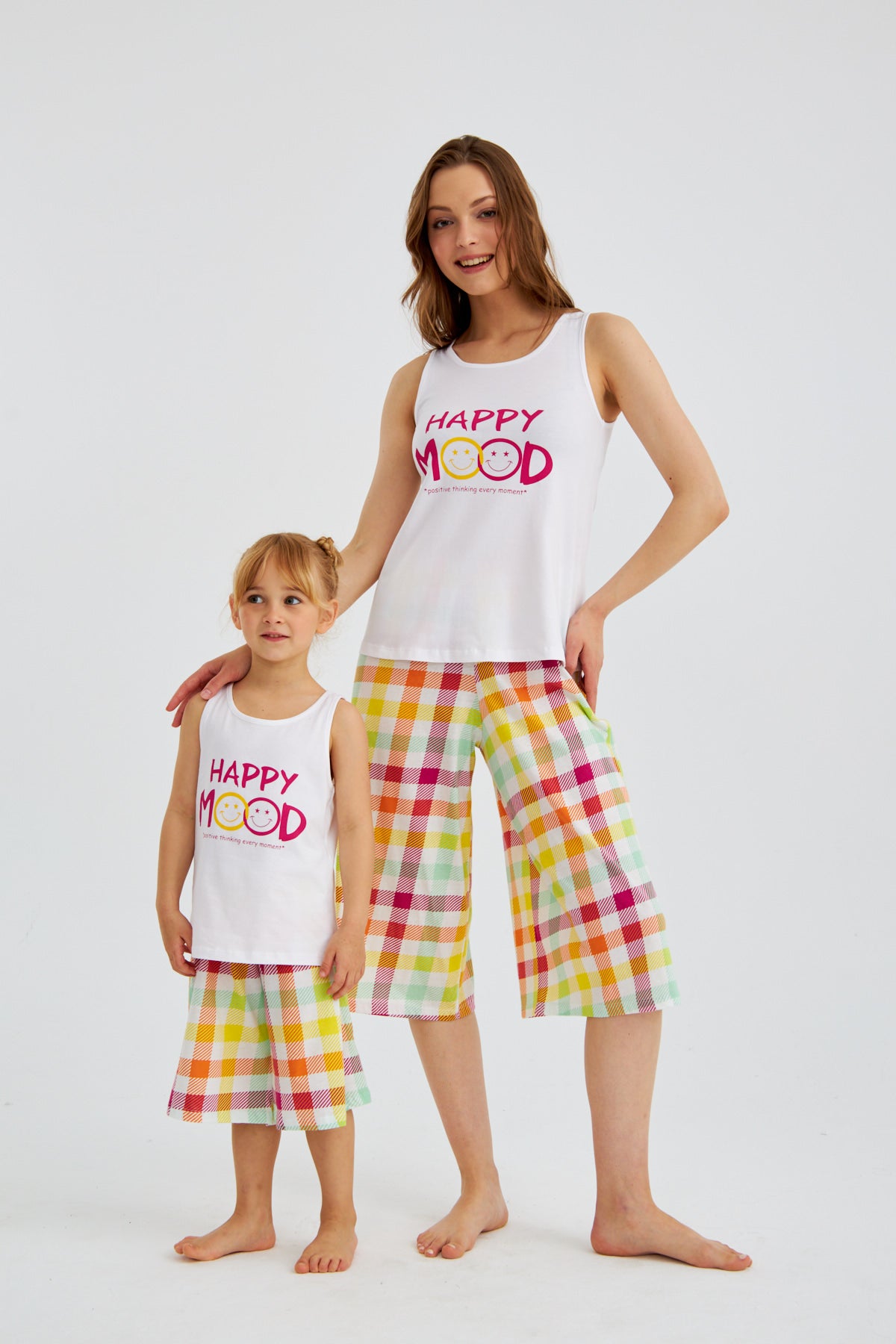 Mother and daughter standing and mother holding her daughter while wearing matching Happy Mood Checkered Pajama Sets from Popjammies.