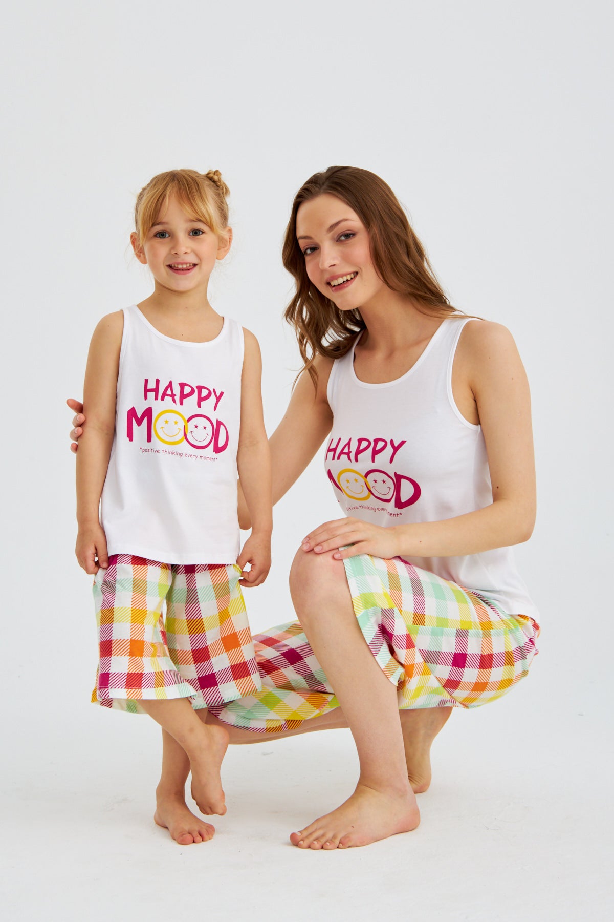 Mother kneeling next to her daughter, both wearing matching Happy Mood Checkered Pajama Sets from Popjammies.