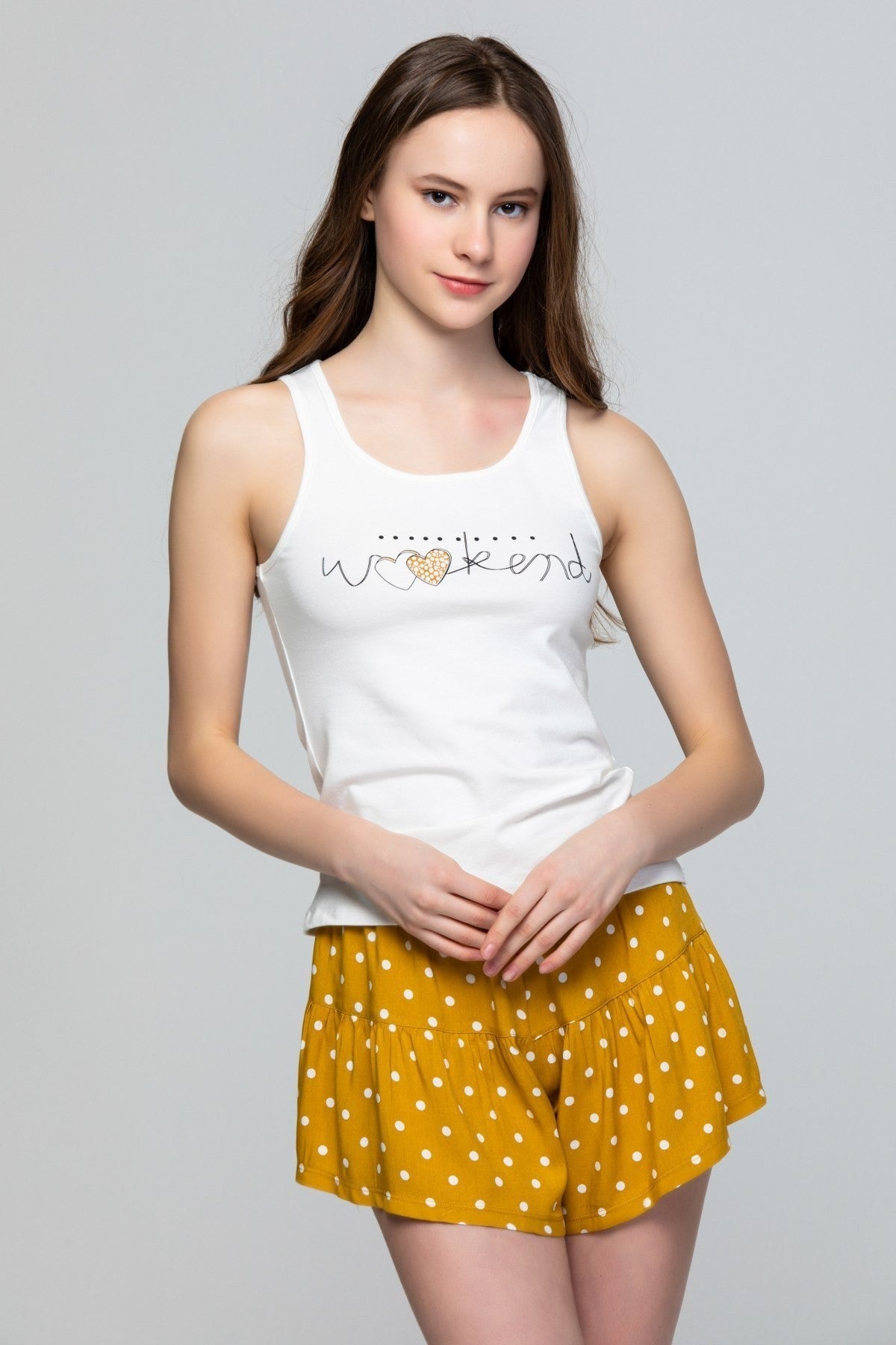 Model wearing Popjammies mustard yellow polka dot skirt with a white tank top