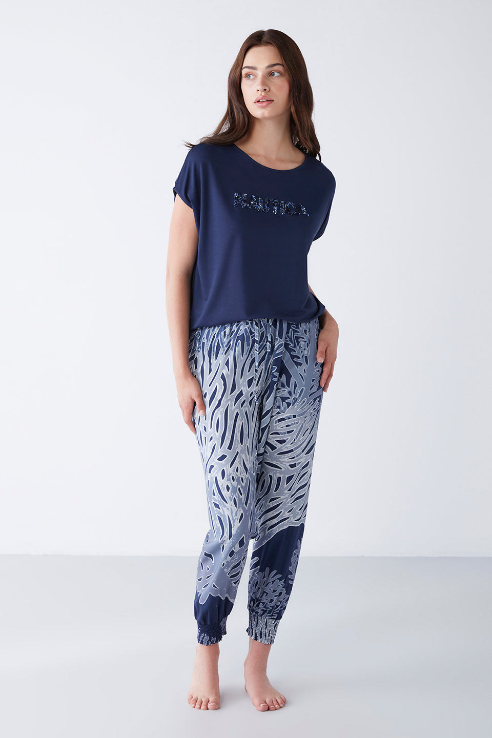 Model wearing a navy blue pyjama set from Popjammies, featuring a navy blue t-shirt with "Beautiful" print and matching patterned pants.