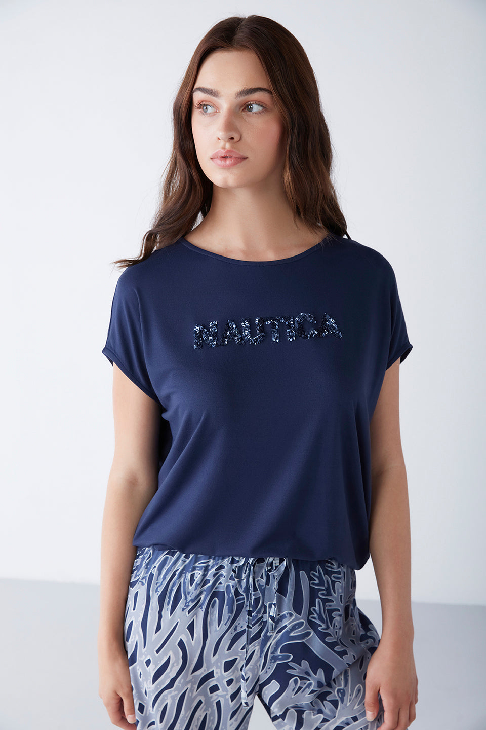 Close-up view of a model wearing Popjammies navy blue pyjama set, featuring a navy blue t-shirt with "Nautica" print and artistic patterned pants.