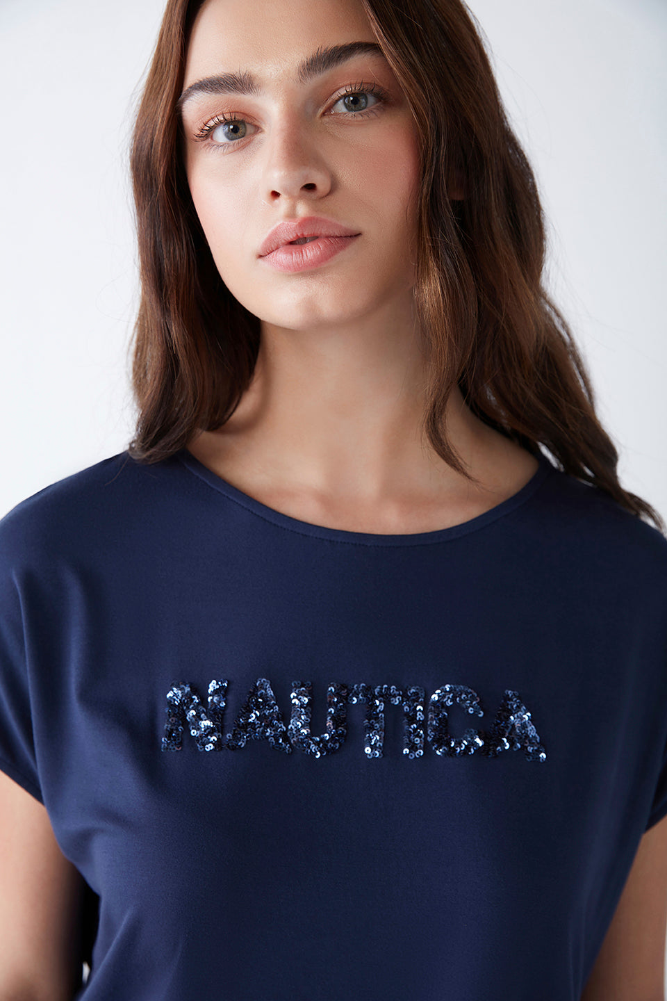 Close-up of a model wearing a navy blue Popjammies pyjama top with the word "Nautica" embroidered in sequins.