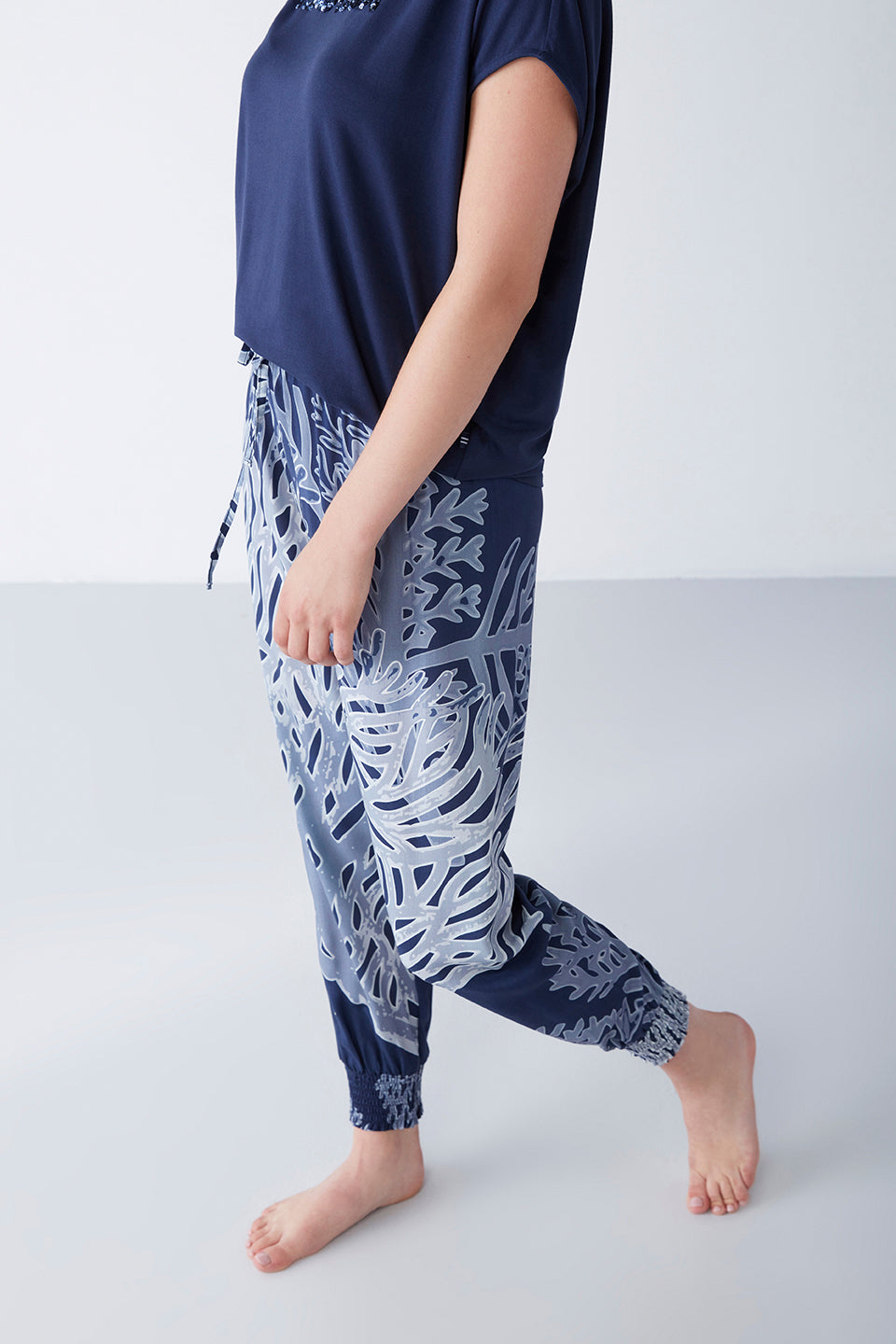 Close-up view of a model wearing Popjammies navy blue pyjama set, featuring a navy blue t-shirt with "Beautiful" print and artistic patterned pants, showing the detailed design of the pants.