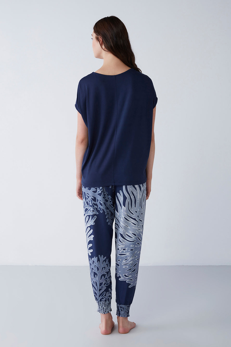 Back view of a model wearing Popjammies navy blue pyjama set, featuring a navy blue t-shirt and artistic patterned pants.