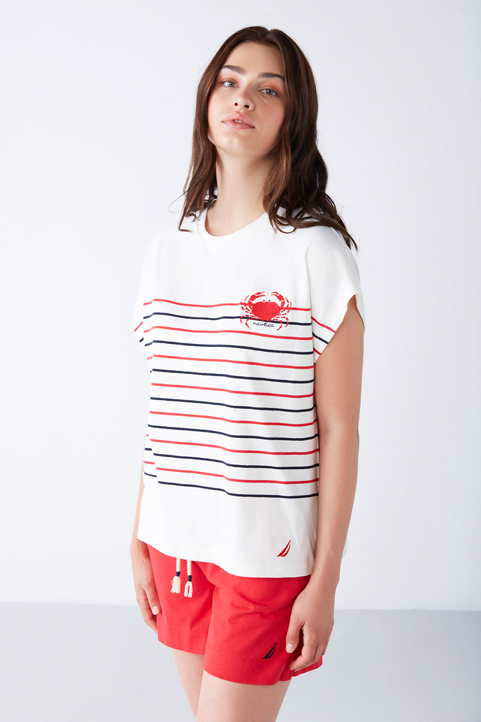 Side view of a woman in a Popjammies nautical striped pyjama set, showing the red crab motif and red shorts.