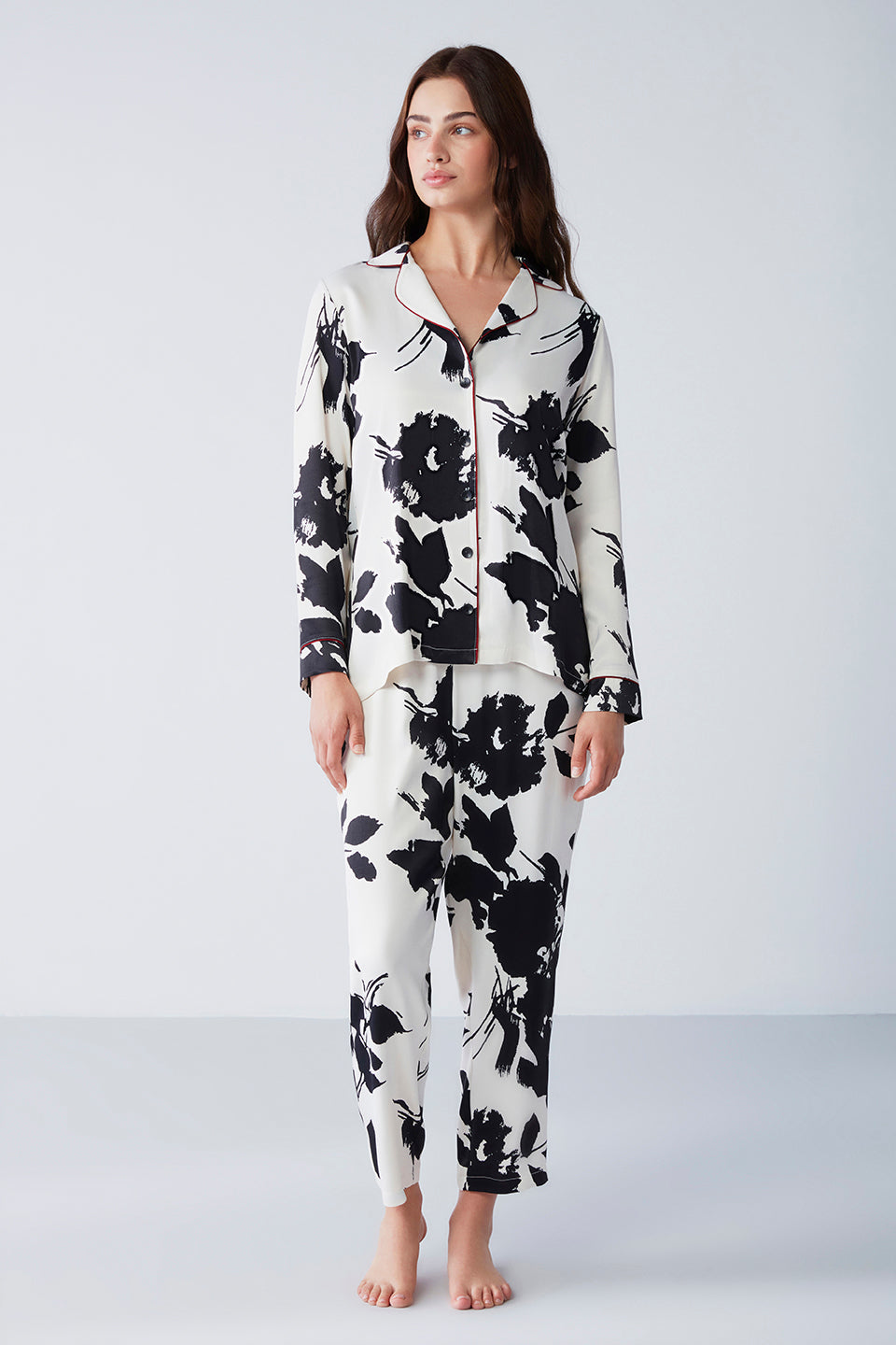 Woman wearing Popjammies "Midnight Blossoms" Pyjama Set featuring a black and white floral print, standing against a white background.