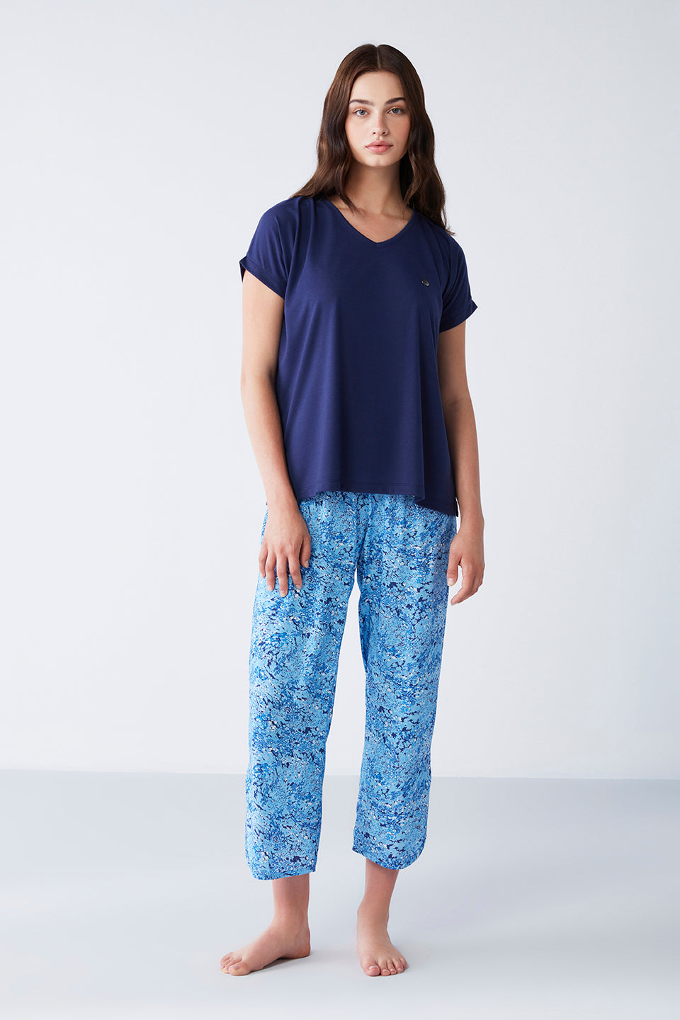 Model wearing Popjammies Women's Pyjama Set with a navy blue V-neck top and blue printed pants, standing against a plain background.