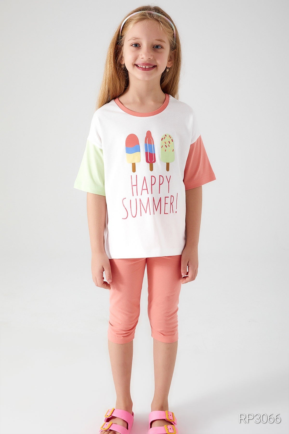 Front view of Popjammies 'Happy Summer' Pajama Set featuring a white top with 'Happy Summer' text and ice cream graphic, with one pastel sleeve and one light green sleeve, paired with pastel pantacour pants, smiling