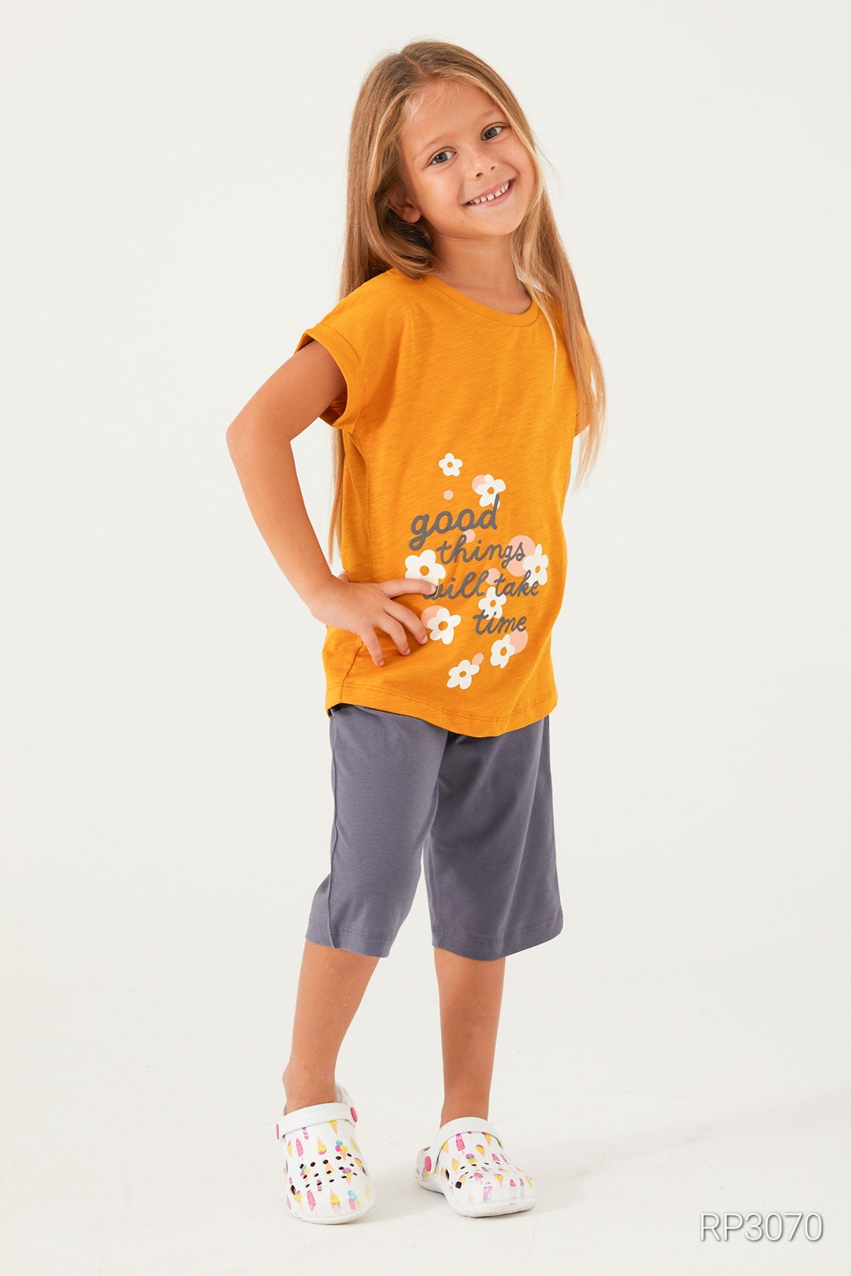  Girl wearing Popjammies Timeless Blooms Pajama Set with mustard top and navy pantacour, smiling with hands on her hips