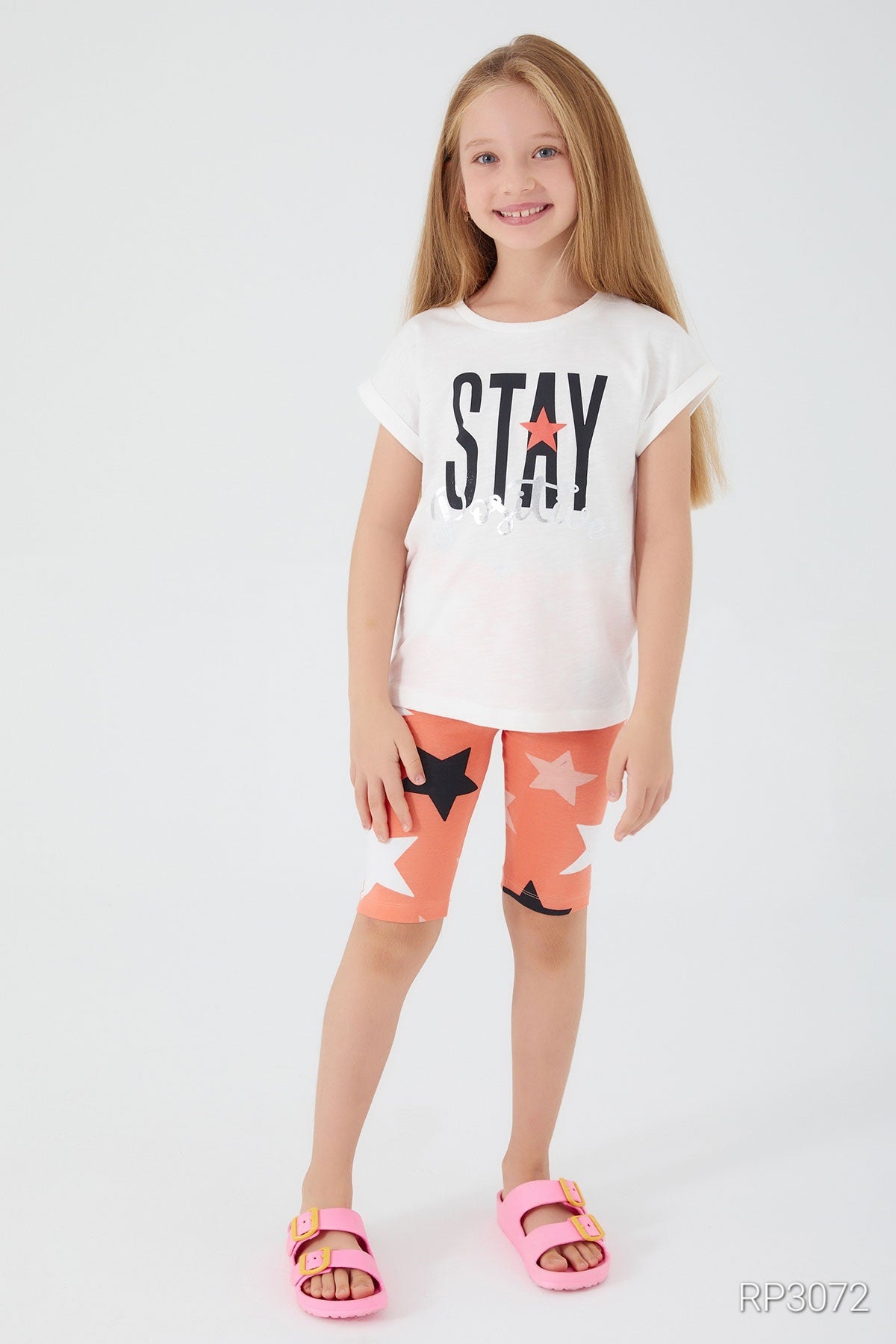 Front view of Popjammies 'Stay Positive' Pajama Set featuring a white top with 'Stay Positive' text and orange legging shorts with stars.