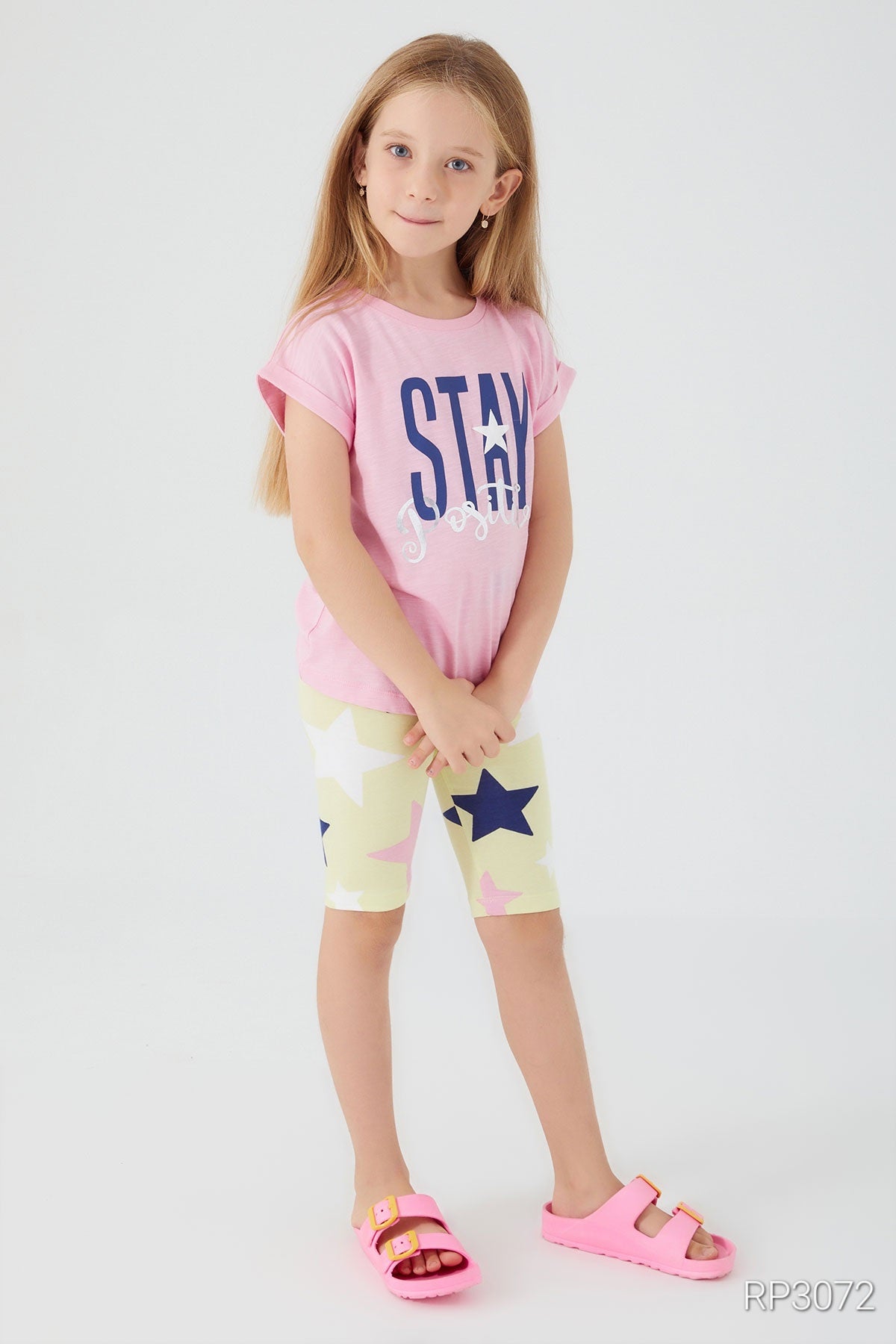 Front view of Popjammies 'Stay Positive' Pajama Set featuring a pink top with 'Stay Positive' text and yellow legging shorts with stars.