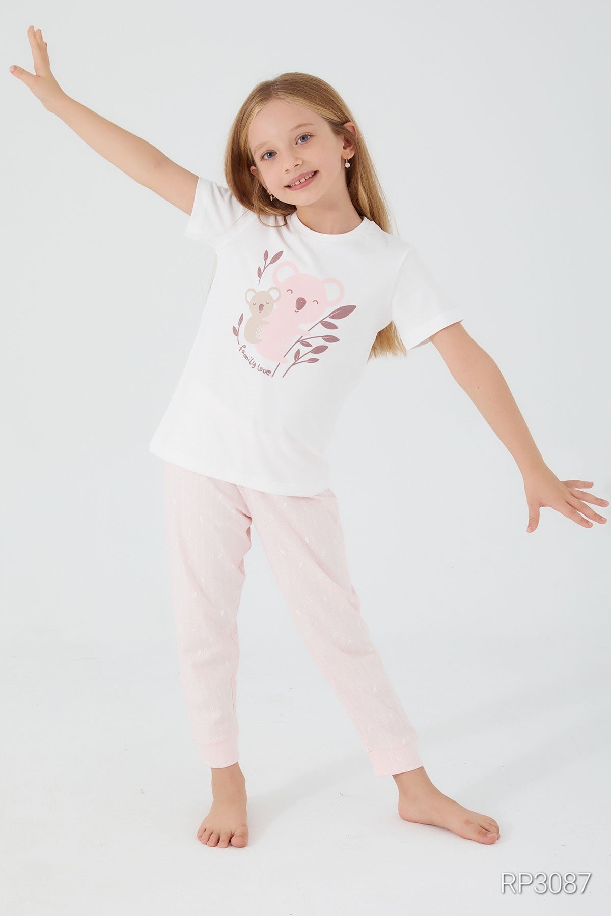 A girl standing with her hands open, wearing a white short sleeve top with bears and "Family Love" text, and light pink pants, front view.