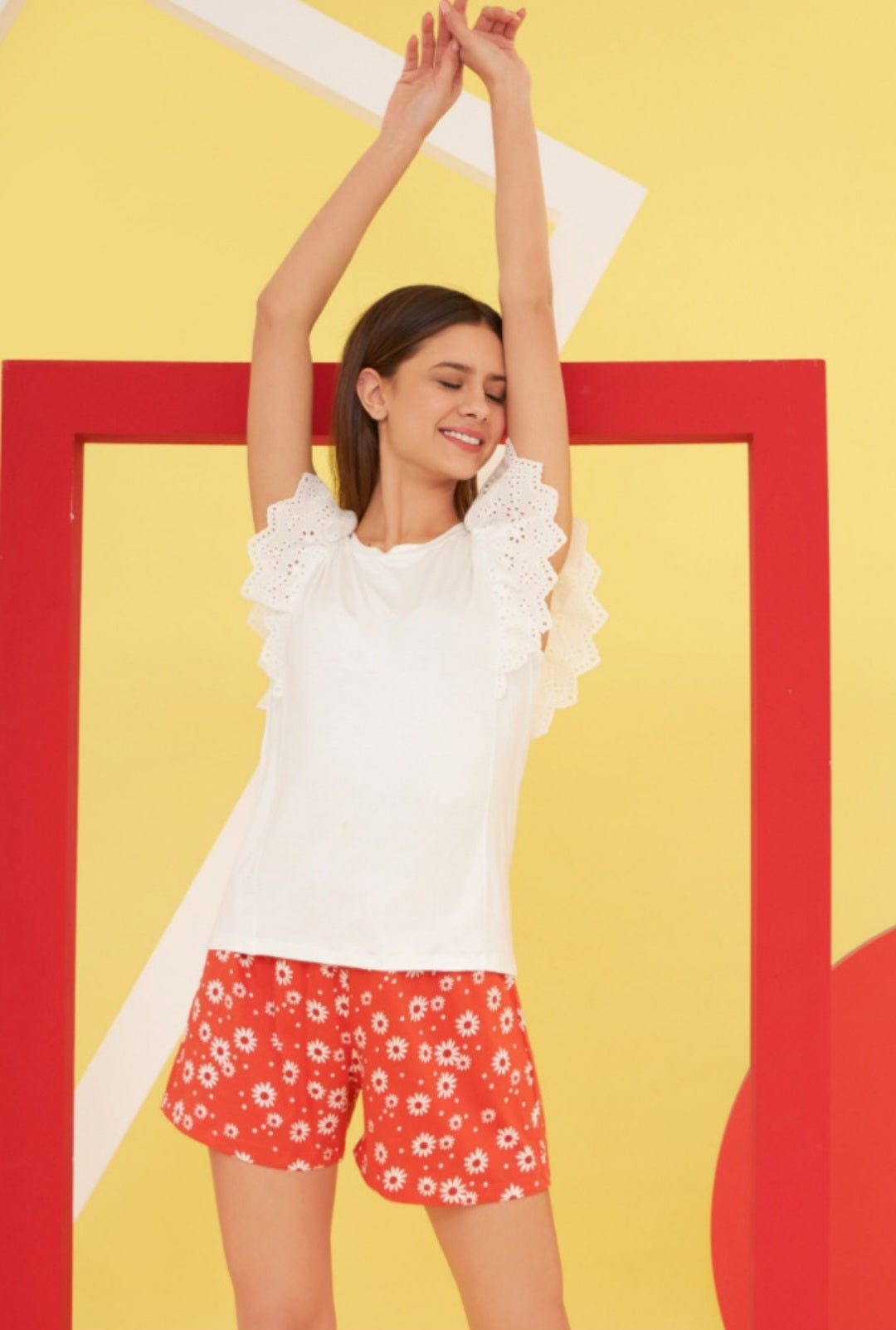 Women's eyelet sleeve pajama set with white top and red daisy print shorts.