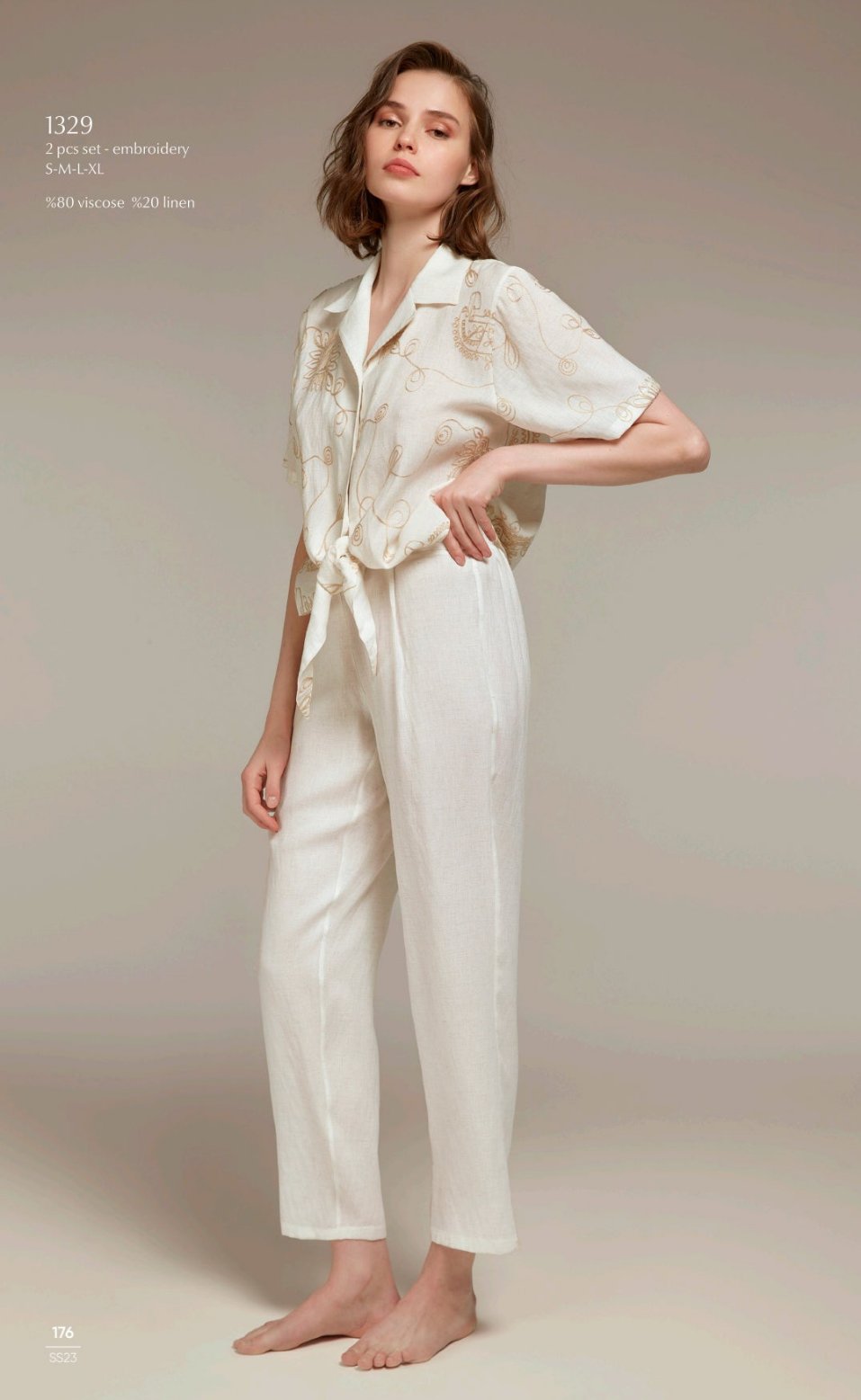 Model wearing Popjammies 1329 Two-Piece Embroidered Pyjama Set in cream, featuring a short-sleeve tie-front top with intricate embroidery and matching high-waisted pants.