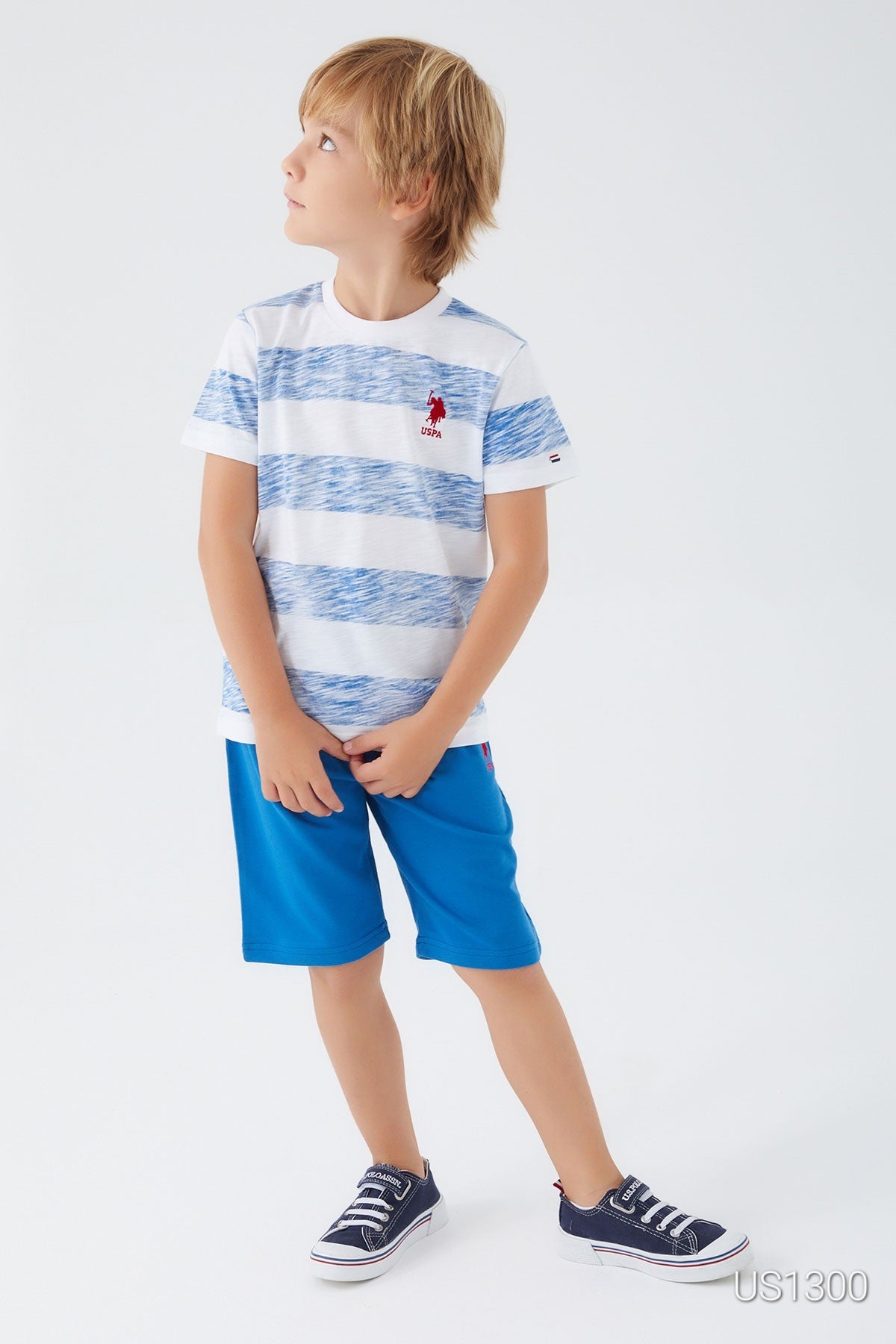 Child looking at the side and wearing Popjammies pyjama set with white top and large light blue patterns, paired with blue shorts 