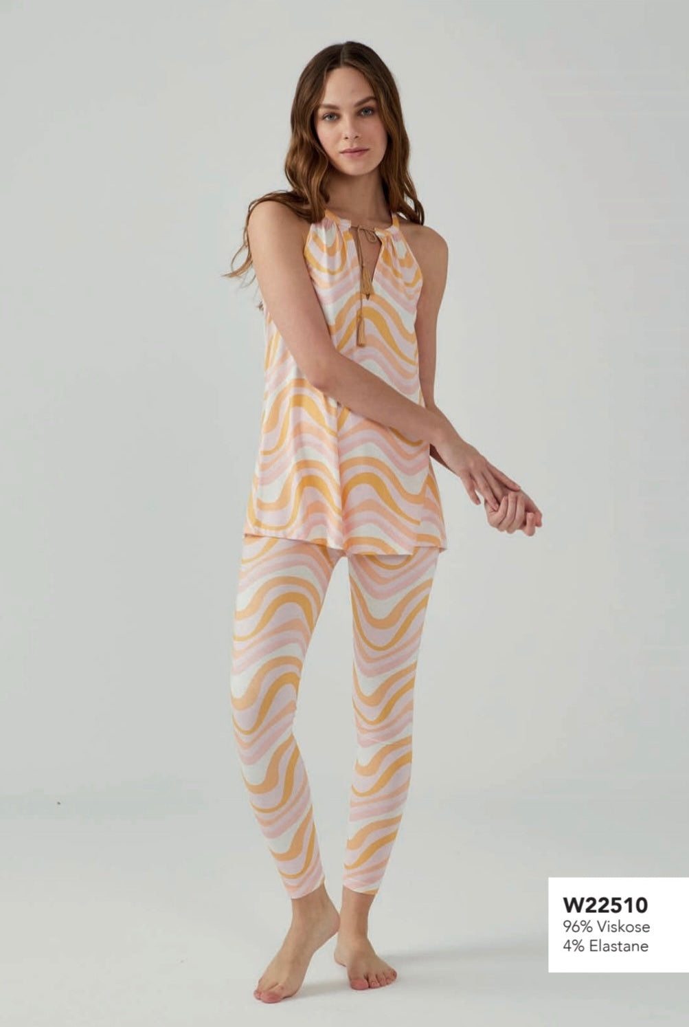 Model wearing Popjammies pastel pink and yellow wave-patterned sleeveless halter top with matching leggings, standing against a plain background.