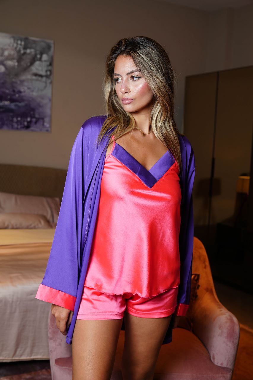 Model showcasing a hot pink satin camisole and shorts with a contrasting purple trim, accompanied by a matching purple robe, from Popjammies.