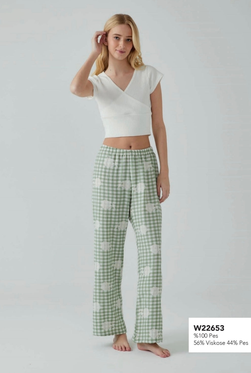 Model wearing a Popjammies green gingham pyjama set, featuring a cropped white ribbed top with a V-neck and relaxed-fit green gingham pants with floral patterns.