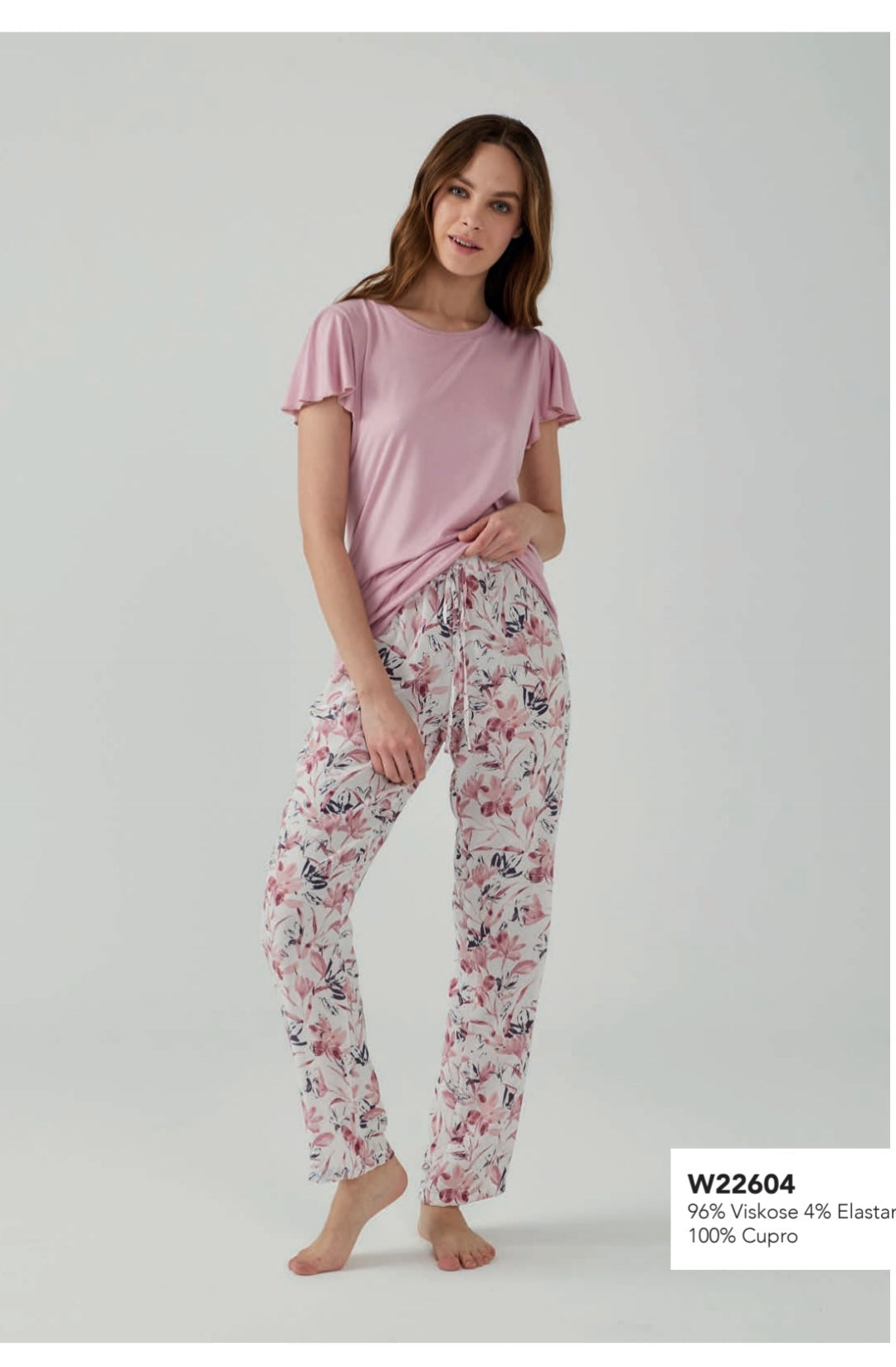 Model wearing a Popjammies lilac flutter sleeve pyjama set, featuring a soft lilac top and white pants with pink and navy floral print.