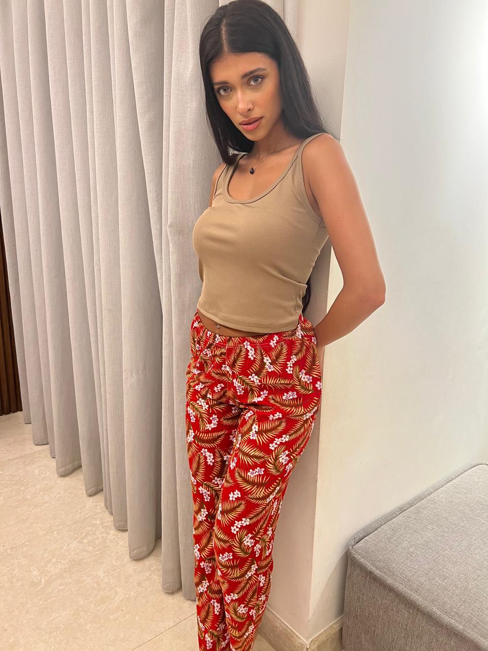 Woman wearing a beige sleeveless top paired with red floral print pants