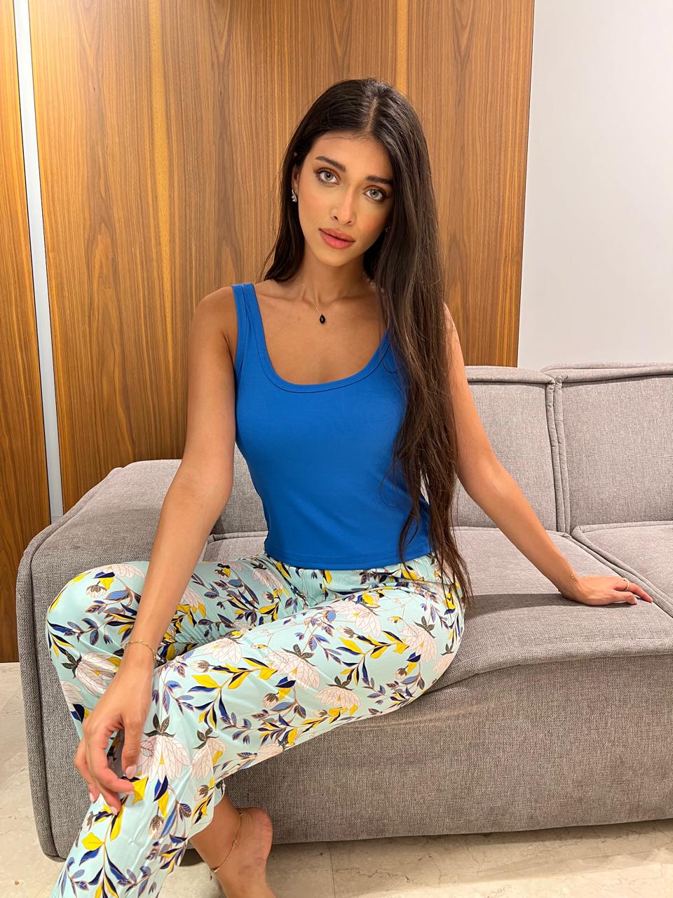 Woman wearing a blue sleeveless top paired with pastel floral print pants 