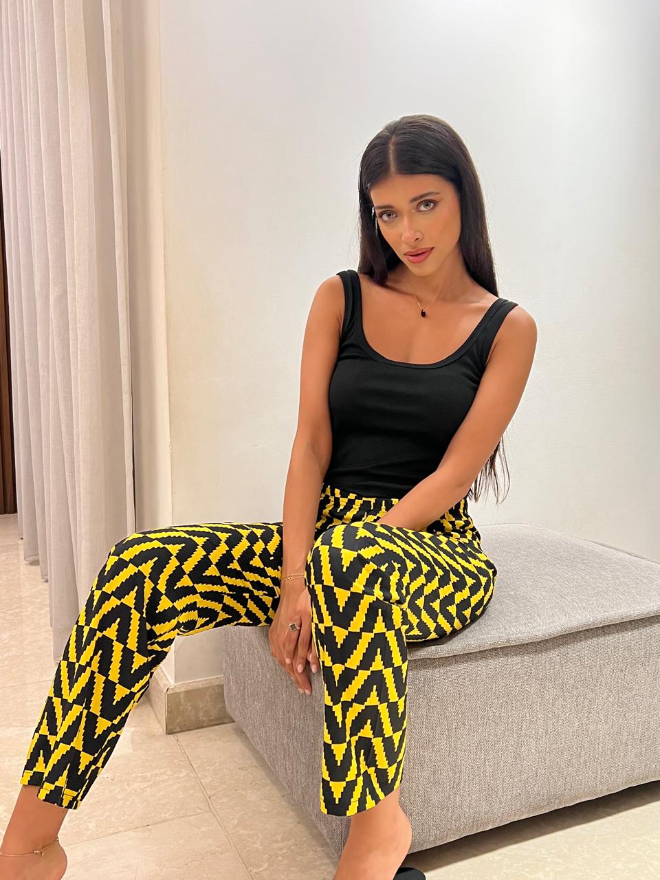 Woman in a black sleeveless top and black and yellow geometric print pants