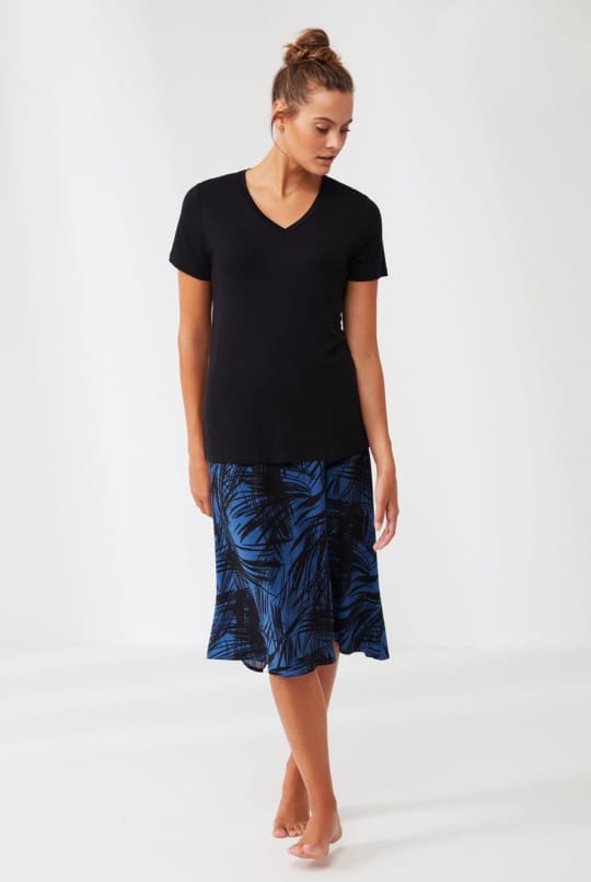 Model wearing Popjammies blue and black palm leaf midi skirt with a black V-neck top