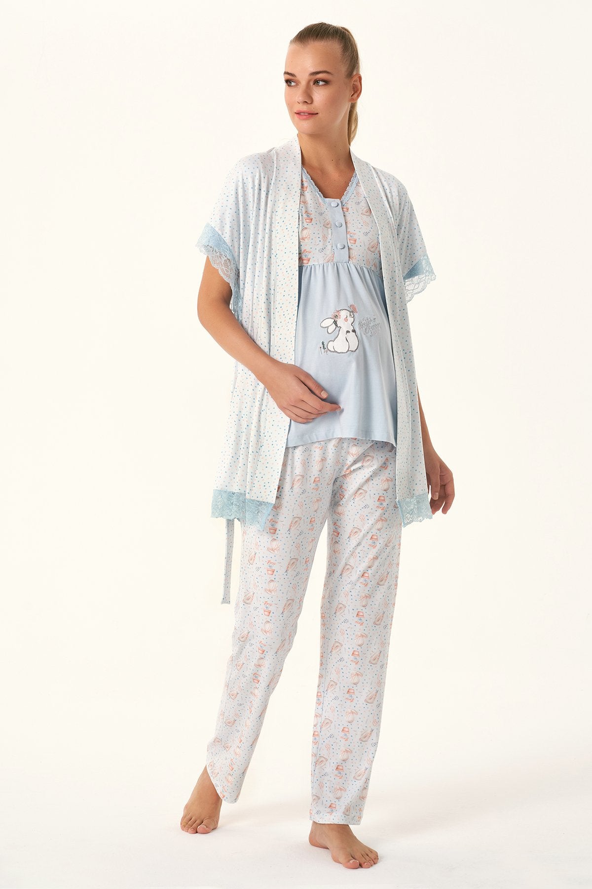 Woman wearing Popjammies Bunny Print Maternity Pajama Set with a light blue top, bunny graphic, matching pants, and a lace-trimmed cardigan.