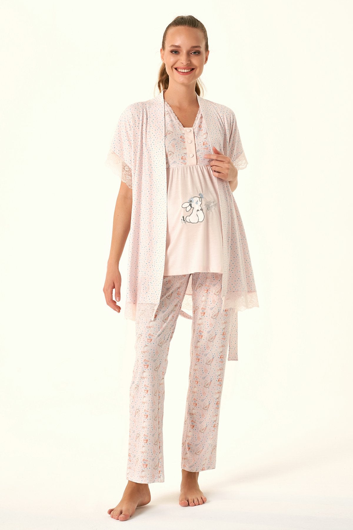 Woman wearing Popjammies Pink Bunny Print Maternity Pajama Set, featuring a pink top with a bunny graphic, matching pants, and a lace-trimmed cardigan.