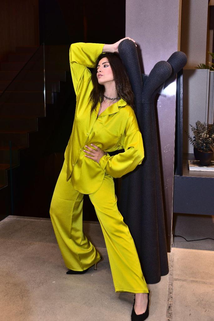 Model wearing a luxurious green silk pyjama set by Popjammies, posing stylishly against a modern interior background.