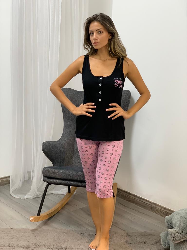 Woman wearing a black tank top paired with pink floral print capri pantacour by Popjammies, standing indoors near a grey chair.