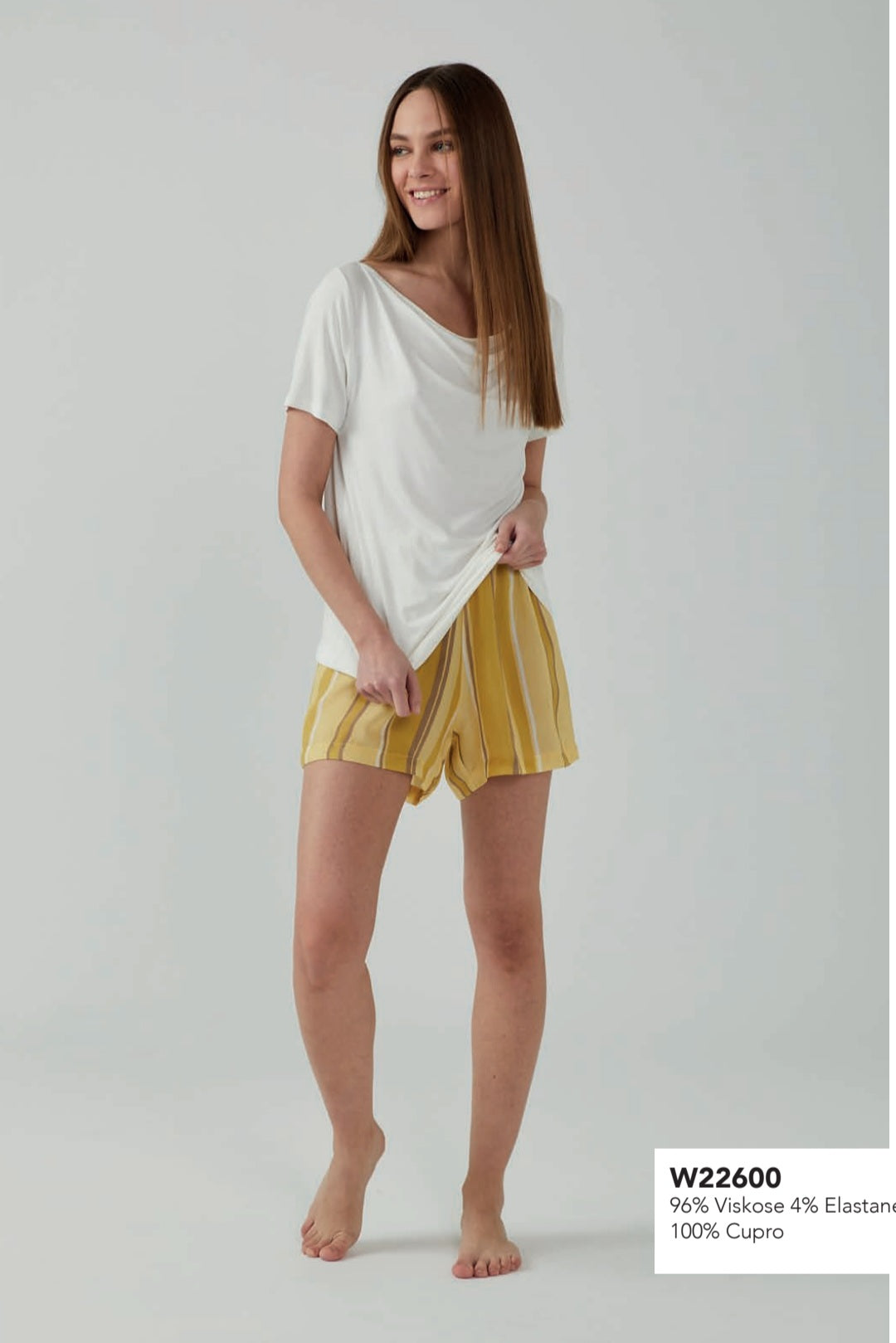 Woman wearing Popjammies Yellow Stripe Pyjama Set with white top and yellow striped shorts.