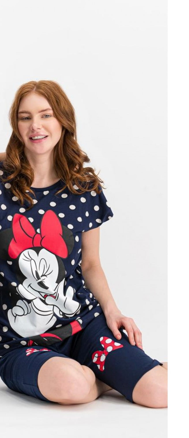 Woman wearing a navy blue short-sleeve top with white polka dots and a Minnie Mouse print, paired with matching navy capri pantacour with bow accents