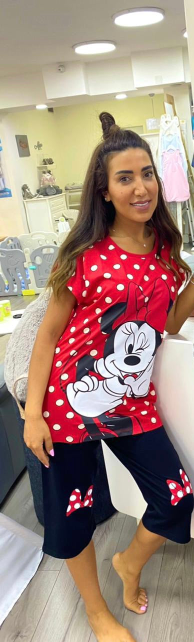 Woman wearing a red short-sleeve top with white polka dots and a Minnie Mouse print, paired with black capri pantacour with bow accents