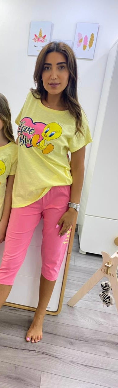 : Woman wearing a yellow short-sleeve top with a Tweety and "Love Bird" print, paired with pink capri pantacour