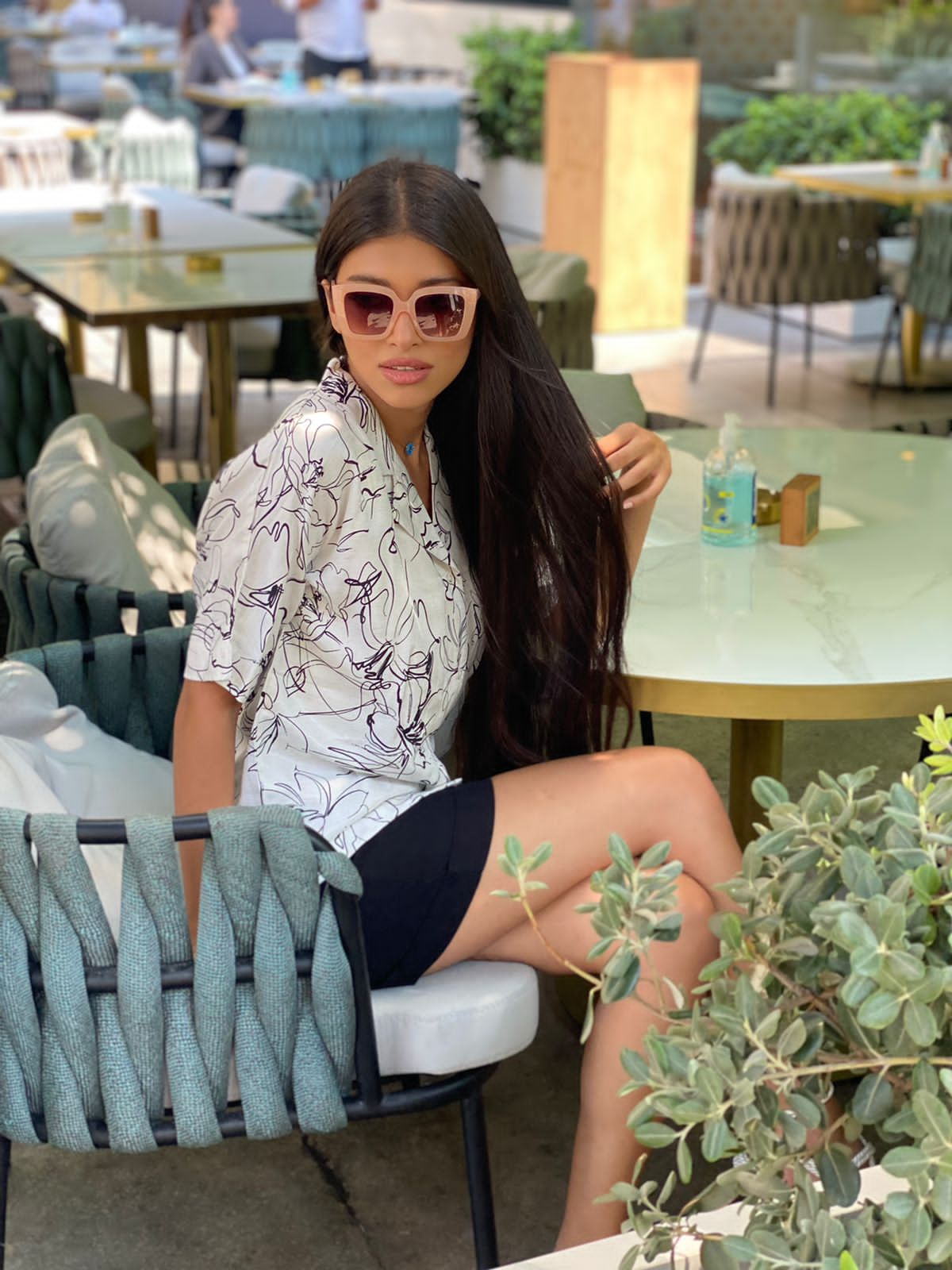 Woman wearing Popjammies Printed Short Sleeve Pyjama Set, sitting outdoors at a cafe.